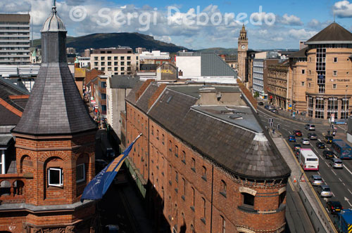 Bar Bittle o Flatiron de Belfast. Este edificio fue construido en 1826, 77 años antes de que el Flatiron en Nueva York. Este edificio en forma de plancha de hierro en un lote de esquina extraña me llamó la atención mientras caminaba a lo largo del lado este del centro de la ciudad. Por desgracia, se sienta en el extremo más alejado de la zona peatonal del centro de la ciudad ya lo largo de una calle de varios carriles y salida de estacionamiento subterráneo, lo que limita la actividad a su alrededor. Creo que al final torrecilla-como, el techo en forma de cono, y la crema de arcos de ladrillo de la ciudad por encima de las ventanas dan al edificio un montón de carácter. Bittle es un siglo 19 triangular edificio de ladrillo rojo decorado con tréboles dorados. El interior en forma de cuña está cubierta de pinturas de los héroes literarios de Irlanda por el artista local Joe O'Kane. El lugar de honor en la pared del fondo es un gran lienzo que representa a Yeats, Joyce, Beckett, Behan y en el bar con vasos de cerveza Guinness, y Wilde tirando de las pintas en el otro lado.