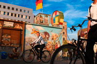 Alemania, Berlín. Bicicletas. Una tarde de relax en el césped de la East Side Gallery, junto al río Spree. La East Side Gallery es un monumento internacional por la libertad. Se trata de una sección de 1,3 kilometros de largo del muro de Berlín, situado cerca del centro de Berlín, en Mühlenstraße en Friedrichshain. La frontera actual en este punto era el río Spree. La galería está ubicada en el llamado "mauer hinterland", que cerró la frontera a Berlín Oriental. La Galería consta de 105 pinturas de artistas de todo el mundo, pintado en 1990 en el lado este del Muro de Berlín.