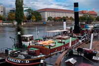 Berlin. Germany. Old Harbour from Inselbruecke, Berlin, Germany. The banks of the Spree in Friedrichshain and the East Harbour offer one of the liveliest and most pleasant ways down to the river to be found in the central city area. The docks are a narrow ribbon, extending one or two kilometres between the river and the six-lane traffic route that accompanies the Spree from the Jannowitzbrücke (Jannowitz Bridge) to the Stralauer Halbinsel (peninsula).  Although there are still gatehouses, visitors can make their way, undisturbed, to the railway tracks, warehouses, loading ramps and huge travelling cranes which load the freight boats with scrap or building materials. In one of the two brick buildings used for management and administration, there was a light friendly canteen with a small summer garden going down to the Spree. 