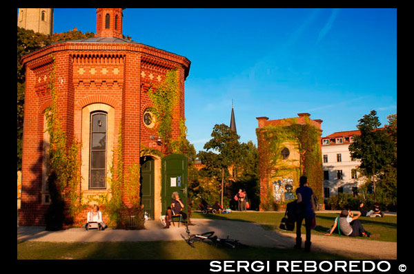 Prenzlauerberg Distrito, jardín alrededor de la antigua Wasserturm, 1873 ladrillos torre de agua convertida en un apartamento. Wasserturm. Watertower en Berlín (Alemania), fue construido en 1877 y es el símbolo de Prenzlauer Berg. El Wasserturm Prenzlauer Berg es la torre de agua más antiguo de Berlín, terminado en 1877 y funcionó hasta 1952. La estructura fue diseñada por Henry Gill y construido por el Inglés Waterworks Company. Se encuentra entre Knaackstraße y Belforter Straße en Kollwitzkiez, en la localidad de Prenzlauer Berg, en Berlín (parte del distrito de Pankow) y trabajó en el principio de la utilización de agua por tubería para abastecer a la creciente población de trabajadores.