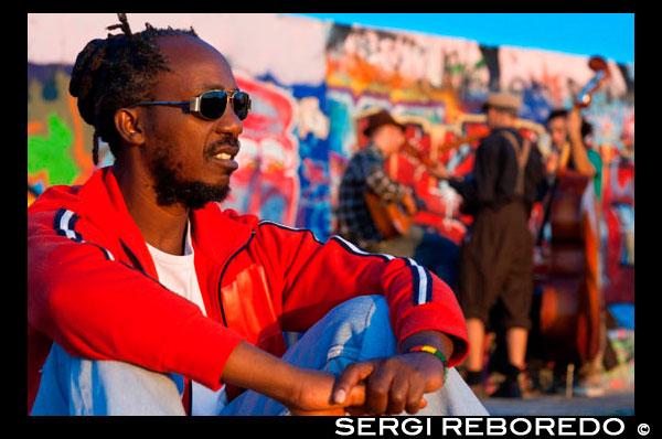 Músicos . Músicos callejeros por el Muro en Mauerpark de Berlín en la noche la luz de Alemania. Mauerpark es un parque lineal pública en el distrito de Prenzlauer Berg de Berlín . El nombre se traduce como " parque de la pared " , en referencia a su condición de ex parte del muro de Berlín y su franja de la muerte . El parque está situado en la frontera de Prenzlauer Berg y el distrito Gesundbrunnen del antiguo Berlín Occidental . En los siglos 19 y 20 , la zona de Parque del Muro sirvió de sede del antiguo Nordbahnhof ( " estación del Norte ") , el término meridional de la prusiana Ferrocarril del Norte abrió sus puertas en 1877/78 , que conecta Berlín con la ciudad de Stralsund y el Mar Báltico. Poco después de que perdió su función como estación de pasajeros a la cercana Stettiner Bahnhof y permaneció en uso como un patio de carga . En 1950, el Stettiner Bahnhof tomó el nombre Nordbahnhof debido a su papel en el sistema de transporte público de Berlín , y el Antiguo Nordbahnhof se conocía como Güterbahnhof Eberswalder Straße. Finalmente se cerró después de la construcción del Muro de Berlín en 1961 . Cuando se mira desde arriba , todavía se pueden ver restos de las vías del ferrocarril que hacia la antigua estación del Ringbahn 