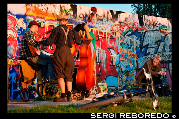 Músicos . Músicos callejeros por el Muro en Mauerpark de Berlín en la noche la luz de Alemania. Mauerpark es un parque lineal pública en el distrito de Prenzlauer Berg de Berlín . El nombre se traduce como " parque de la pared " , en referencia a su condición de ex parte del muro de Berlín y su franja de la muerte . El parque está situado en la frontera de Prenzlauer Berg y el distrito Gesundbrunnen del antiguo Berlín Occidental . En los siglos 19 y 20 , la zona de Parque del Muro sirvió de sede del antiguo Nordbahnhof ( " estación del Norte ") , el término meridional de la prusiana Ferrocarril del Norte abrió sus puertas en 1877/78 , que conecta Berlín con la ciudad de Stralsund y el Mar Báltico. Poco después de que perdió su función como estación de pasajeros a la cercana Stettiner Bahnhof y permaneció en uso como un patio de carga . En 1950, el Stettiner Bahnhof tomó el nombre Nordbahnhof debido a su papel en el sistema de transporte público de Berlín , y el Antiguo Nordbahnhof se conocía como Güterbahnhof Eberswalder Straße. Finalmente se cerró después de la construcción del Muro de Berlín en 1961 . Cuando se mira desde arriba , todavía se pueden ver restos de las vías del ferrocarril que hacia la antigua estación del Ringbahn 