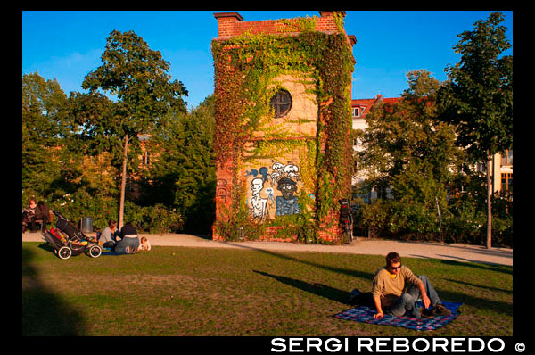 Prenzlauerberg Distrito, jardín alrededor de la antigua Wasserturm, 1873 ladrillos torre de agua convertida en un apartamento. Wasserturm. Watertower en Berlín (Alemania), fue construido en 1877 y es el símbolo de Prenzlauer Berg. El Wasserturm Prenzlauer Berg es la torre de agua más antiguo de Berlín, terminado en 1877 y funcionó hasta 1952. La estructura fue diseñada por Henry Gill y construido por el Inglés Waterworks Company. Se encuentra entre Knaackstraße y Belforter Straße en Kollwitzkiez, en la localidad de Prenzlauer Berg, en Berlín (parte del distrito de Pankow) y trabajó en el principio de la utilización de agua por tubería para abastecer a la creciente población de trabajadores.