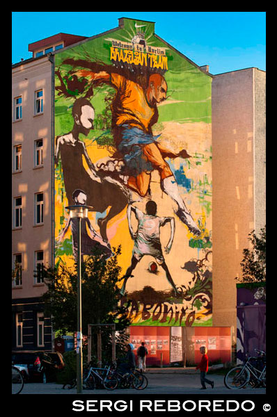Graffiti in a house near the Mauerpark, Berlin in evening light Germany. Wellcome to Belin, brazilian team. Joga bonito. Mauerpark is a public linear park in Berlin's Prenzlauer Berg district. The name translates to "Wall Park", referring to its status as a former part of the Berlin Wall and its Death Strip. The park is located at the border of Prenzlauer Berg and Gesundbrunnen district of former West Berlin. In the 19th and 20th centuries, the Mauerpark area served as the location of the Old Nordbahnhof ("Northern Railway Station"), the southern terminus of the Prussian Northern Railway opened in 1877-78, which connected Berlin with the city of Stralsund and the Baltic Sea. Soon after it lost its role as a passenger station to the nearby Stettiner Bahnhof and remained in use as a freight yard. In 1950 the Stettiner Bahnhof took the name Nordbahnhof because of its role in Berlin's public transportation system, and the Old Nordbahnhof became known as Güterbahnhof Eberswalder Straße. It was finally closed after the building of the Berlin Wall in 1961. When viewed from above, one can still see remains of the railroad tracks running towards the former station from the Ringbahn.