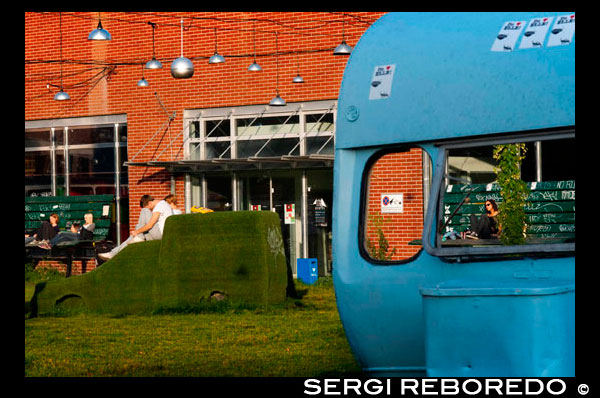 Berlín , Alemania, el Jardín de la desaceleración Arena flota Berlín. Bancos de gran tamaño y coches cubiertos de hierba en el Arena de Berlín. Eventos culturales en un edificio de la fábrica que aparece a lo largo de la antigua frontera de la RDA . Hoy en día, este 7000 lugar m² en el borde del río Spree es el sitio para innumerables conciertos, ferias y fiestas -, pero el complejo de edificios en el distrito de Treptow de Berlín fue originalmente utilizado de manera muy diferente : Diseñado por el arquitecto Franz Ahrens, el estadio fue construido en 1927 como una sala de bus para el sistema de transporte público de Berlín . En ese momento , era la sala más grande de independiente de Europa y podría contener 240 autobuses. Durante el período nazi , se convirtió en un arsenal de armas . Después de que el Muro de Berlín fue construido en 1961 , ya no era accesible debido a su ubicación ; después de la reunificación alemana, los servicios de transporte público de Berlín cerró oficialmente el edificio por completo. Varios lugares en un área A mediados de los años 1990 , extensas reformas se llevaron a cabo en el complejo , y la Arena de Berlín es ahora uno de los lugares más importantes para los eventos culturales de la ciudad . La Arena se ha expandido a través de los años para incluir lugares adicionales en los alrededores. La " casa de cristal " de la Arena, un club, teatro y café , por ejemplo, se encuentra en lo que fue el taller de un tornero , que ofrece vistas panorámicas al río Spree , con su fachada totalmente acristalada. Las vistas también se pueden disfrutar desde a bordo del club y restaurante buque MS Hoppetosse , que se ancla a lo largo de las orillas del río Spree . El barco también ofrece una fiesta reggae de todos los domingos, titulado ' Yaam ' . La nave vecina cuenta con una piscina en el verano con un montón de espacio para tomar el sol , y se convierte en un paisaje de sauna con techo en invierno. Otros lugares de celebración de la Arena de Berlín incluyen la Arena Club, el restaurante ' Anhalt ' y el bar ' Freischwimmer ' . Los meses de verano son un tiempo muy ocupado aquí , con conciertos , fiestas, varios eventos anuales , como el festival de música ' Popdeurope ' Europeo y al aire libre ' Unplugged '