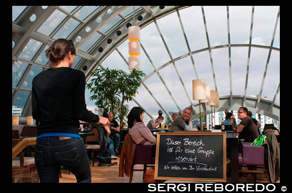 Gente en un restaurante en el centro comercial de lujo KaDeWe de Berlín Alemania . Grandes almacenes más famosos de la marca de Berlín, KaDeWe ( Kaufhaus des Westens ) - o grandes almacenes de Occidente. Es el paraíso comercial de Berlín , una de las favoritas , fácil de lugar tan emblemático en Wittenberg Platz. Con 60.000 metros cuadrados , el equivalente a nueve campos de fútbol, ??380 000 artículos, 40 000 visitantes al día , este es el legendario almacén más grande en el continente. Los grandes almacenes , propiedad del empresario minorista judío Adolf Jandorf , abrió por primera vez en Wittenberg Platz en 1907 con una superficie de venta al público de 24.000 metros cuadrados. Diseñado por el arquitecto Emil Schaudt , que sirvió a la cada vez más rico barrio de clase media del nuevo distrito de Tiergarten. En 1927 fue comprado por el Warenhaus Hermann Tiez AG desde cuyas iniciales el gigante minorista alemán Hertie recibe su nombre pasando a formar parte del grupo. Fundadores de Hertie , la familia Tietz judía , en el negocio desde 1882, hizo historia al por menor por ser pionero en el nuevo modelo de negocio , adquirida por Hermann durante su tiempo en los EE.UU. ; grandes pérdidas de balón en el pequeño beneficio y la venta a precios fijos. Tietz compró la tienda de Adolfo Jandorf - KaDeWe - por 1926 Fue en ese momento en que el almacén más grande de Europa, con una facturación de 128 millones de RM y 18.000 empleados. . En 1931 se añadieron dos pisos a las originales cinco y más extensiones se produjo en la década de 1990 , en particular la parte superior de la azotea mundo y Wintergarten donde el restaurante self-service es hoy.