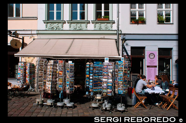 Seller postscard. Horizontal view of a traditional old toy and postcards shop selling teddy bears and souvenirs in the historic district of Nikolaiviertel. This is a most fantastic shop in Nikolaiviertel. Even if you do not intend to buy a doll, just browse through the shop like through a museum. The dolls are simply wonderful, from historic editions to the most modern girls, plus a big selection of dolls’ clothes and prams.   They store all famous dolls brands like Käte Kruse, Zapf, Schildkröt, Philip Heath, Götz and so on. On their website you find the complete selection of artists, many in limited edition. Be prepared to pay 300 Euro for a bargain… So do not fall in love too fast with any of the dolls before checking your bank account.  Apart from dolls, they sell cute teddy bears, and also Berlin souvenir bears, called Buddy Bears. 