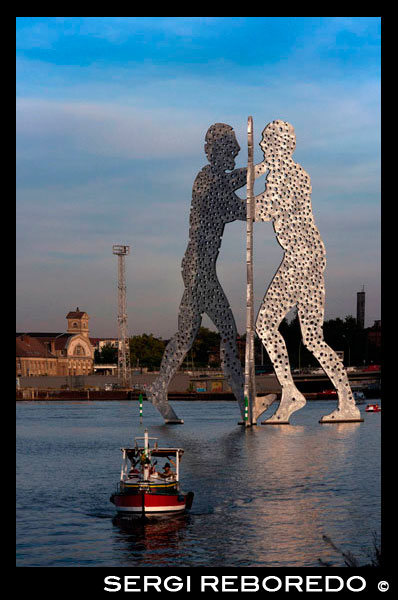 Metallic sculpture called Molecule Man by Jonathan Borofsky in Spree River Berlin. Molecule Man is a series of aluminium sculptures, designed by American artist Jonathan Borofsky, installed at various locations in the world, including Berlin, Germany, and Council Bluffs, Iowa, USA. The first Molecule Man sculptures were made in 1977 and 1978 in Los Angeles, USA. The sculptures consist of three humans leaning towards each other, the bodies of which are filled with hundreds of holes, the holes representative of "the molecules of all human beings coming together to create our existence". A related sculpture is the Hammering Man