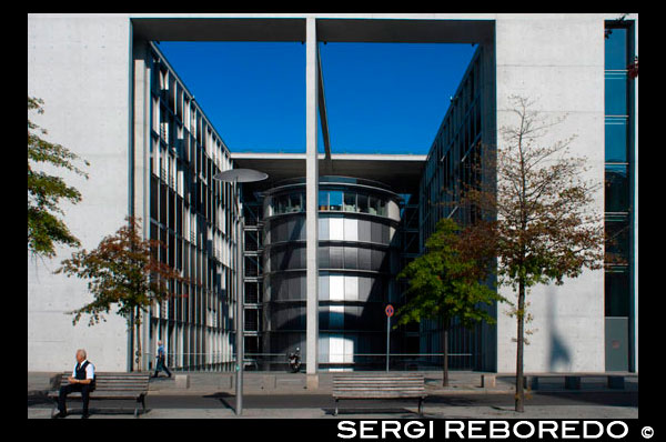 Paul Loebe House, Germany, Berlin. The glass-and-concrete Paul-Löbe-Haus houses offices for the Bundestag’s parliamentary committees. From above it looks like a double-sided comb and on the inside there’s an atrium long enough to be a bowling alley for giants. It’s linked by a double footbridge to the Marie-Elisabeth-Lüders-Haus across the Spree in a visual symbol of reunification. Opening hours vary, depending on parliamentary use. The building named after Paul Löbe, President of Germany’s Reichstag from 1924 - 32, is one of the most impressive federal government buildings on Berlin‘s Spreebogen riverbank. Providing 32,000 m² of floor space distributed over eight storeys, the complex houses 550 offices for 275 parliamentarians, 21 meeting rooms for committees, with various visitors' galleries, 400 offices, 8 seminar rooms, two restaurants and the headquarters of the Committee on the Affairs of the European Union.  Transparency meets solidity Despite the building’s massive structural dimensions, its architect, Stephan Braunfels, succeeded in creating a design of filigree lightness for the parliament of the German Bundestag. The Munich architect, whose design convinced the jury in the competition for the contract to design and construct the building, relies largely on the use of glass. All of the building’s eight storeys are enclosed in an elongated hall, whose house-high glass walls provide views into and through it.  The committee rooms, also situated in rotundas, can be looked into from the hall, giving an impression of openness and transparency. Huge, 23 metre-high porches held up by slender columns represent a further decisive style element. These not only emphasise the building’s east-west orientation, they also correspond with the structure of the Marie-Elisabeth Lüders Building on the opposite bank of the River Spree. This architectural device has helped create an appealing interconnected ensemble, which is linked by a bridge.  To avoid detracting from the building‘s harmonious appearance, its electro-technical equipment had to be integrated into its surroundings as unobtrusively as possible, both in terms of form and colour.  JUNG’s LS 990 range of switches in stainless steel, which perfectly meets these criteria, was therefore the logical choice.