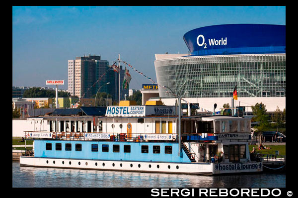 Berlin O2 World Spree Hostel Eastern Comfort. The hostel boats 'Eastern Comfort & Western Comfort', looks forward to welcoming you onboard with its unusual atmosphere which is unique to Berlin!  The 'Eastern Comfort' is composed with 1st and 2nd class cabins all of them ensuite. Choose between the spacious 1st class cabins, with large windows, natural lighting and thus spectacular views of the Berlin Wall or the river Spree. Minibar and Tv available on request. Or view Berlin through the portholes of our 2nd class cabins, smaller but cosy. Also equipped with 3 and 4 beds. Western Comfort the new boat is moored on the opposite of the Spree River ( 250m walking distance) western riverside, in Kreuzberg, West-Berlin. Perfect for low budget travellers because all the cabins from 1 up to 3 beds, with shared showers and toilets. The shared community bathrooms are centrally located on the upper deck and the spacious roof terrace sets the perfect setting for relaxing and absorbing Berlin. The boat is equipped with a modern central heating system in every cabin to ensure comfort and enjoy the crackling fire in our stoves while eating breakfast, during colder times of the year. Half our cabins on the boats have water view, the other half land view of the Berlin Wall. The earlier you book, the longer you stay with us the greater the chance to get a cabin with water view :-) PLEASE NOTE: Berlin is under construction! The Spree river on the Western side is being renovated. Effective immediately, our Western boat is in exile on the eastern side of the Spree river for a number of months. Our guests will be happy because they will have only to walk 1min to their cabins after checking in! East & West side by side; looking forward to seeing you on board(s)'  Moreover from the 01.02.2013 : Bedding & towel will be included in 1,2,3 & 4 beds cabins 2nd class Eastern.
