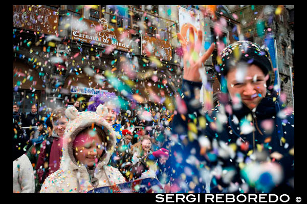 Confetti in the Town Hall Square. Music, dance, party and costumes in Binche Carnival. Ancient and representative cultural event of Wallonia, Belgium. The carnival of Binche is an event that takes place each year in the Belgian town of Binche during the Sunday, Monday, and Tuesday preceding Ash Wednesday. The carnival is the best known of several that take place in Belgium at the same time and has been proclaimed as a Masterpiece of the Oral and Intangible Heritage of Humanity listed by UNESCO. Its history dates back to approximately the 14th century. Events related to the carnival begin up to seven weeks prior to the primary celebrations. Street performances and public displays traditionally occur on the Sundays approaching Ash Wednesday, consisting of prescribed musical acts, dancing, and marching. Large numbers of Binche's inhabitants spend the Sunday directly prior to Ash Wednesday in costume. The centrepiece of the carnival's proceedings are clown-like performers known as Gilles. Appearing, for the most part, on Shrove Tuesday, the Gilles are characterised by their vibrant dress, wax masks and wooden footwear. They number up to 1,000 at any given time, range in age from 3 to 60 years old, and are customarily male. The honour of being a Gille at the carnival is something that is aspired to by local men