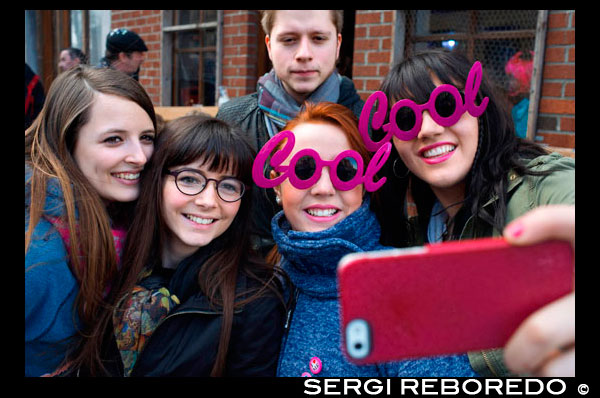 Teenagers taking selfies himself with pink fashion glasses of Cool. Music, dance, party and costumes in Binche Carnival. Ancient and representative cultural event of Wallonia, Belgium. The carnival of Binche is an event that takes place each year in the Belgian town of Binche during the Sunday, Monday, and Tuesday preceding Ash Wednesday. The carnival is the best known of several that take place in Belgium at the same time and has been proclaimed as a Masterpiece of the Oral and Intangible Heritage of Humanity listed by UNESCO. Its history dates back to approximately the 14th century. Events related to the carnival begin up to seven weeks prior to the primary celebrations. Street performances and public displays traditionally occur on the Sundays approaching Ash Wednesday, consisting of prescribed musical acts, dancing, and marching. Large numbers of Binche's inhabitants spend the Sunday directly prior to Ash Wednesday in costume. The centrepiece of the carnival's proceedings are clown-like performers known as Gilles. Appearing, for the most part, on Shrove Tuesday, the Gilles are characterised by their vibrant dress, wax masks and wooden footwear. They number up to 1,000 at any given time, range in age from 3 to 60 years old, and are customarily male. The honour of being a Gille at the carnival is something that is aspired to by local men