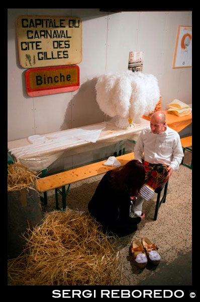 Vestir a casa per al Carnaval de Binche. Preparació, preparatius, va posar el vestit. El carnaval de Binche és un esdeveniment que té lloc cada any a la ciutat belga de Binche durant el diumenge, dilluns i dimarts previs al Dimecres de Cendra. El carnaval és el més conegut dels diversos que té lloc a Bèlgica, a la vegada i s'ha proclamat, com a Obra Mestra del Patrimoni Oral i Immaterial de la Humanitat declarat per la UNESCO. La seva història es remunta a aproximadament el segle 14. Esdeveniments relacionats amb el carnaval comencen fins set setmanes abans de les celebracions principals. Espectacles de carrer i exhibicions públiques es produeixen tradicionalment en els diumenges s'acosta al Dimecres de Cendra, que consisteix en actes prescrits musicals, danses i marxes. Un gran nombre d'habitants de Binche passen el diumenge directament abans del Dimecres de Cendra en el vestit. La peça central dels treballs del carnaval són executants de pallasso conegut com Gilles. Apareixent, en la seva major part, el dimarts de Carnaval, el Gilles es caracteritzen per les seves vestit vibrant, màscares de cera i calçat de fusta. El seu nombre és fins a 1000 en un moment donat, el rang d'edats entre 3 i 60 anys d'edat, i són habitualment masculí. L'honor de ser una Gille al carnaval és una cosa que s'aspira per homes locals