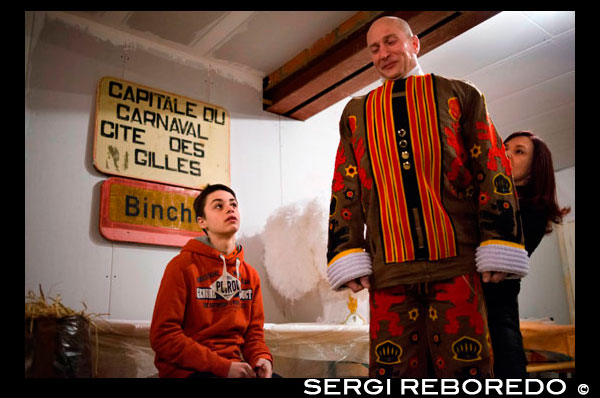 Vestir a casa per al Carnaval de Binche. Preparació, preparatius, va posar el vestit. El carnaval de Binche és un esdeveniment que té lloc cada any a la ciutat belga de Binche durant el diumenge, dilluns i dimarts previs al Dimecres de Cendra. El carnaval és el més conegut dels diversos que té lloc a Bèlgica, a la vegada i s'ha proclamat, com a Obra Mestra del Patrimoni Oral i Immaterial de la Humanitat declarat per la UNESCO. La seva història es remunta a aproximadament el segle 14. Esdeveniments relacionats amb el carnaval comencen fins set setmanes abans de les celebracions principals. Espectacles de carrer i exhibicions públiques es produeixen tradicionalment en els diumenges s'acosta al Dimecres de Cendra, que consisteix en actes prescrits musicals, danses i marxes. Un gran nombre d'habitants de Binche passen el diumenge directament abans del Dimecres de Cendra en el vestit. La peça central dels treballs del carnaval són executants de pallasso conegut com Gilles. Apareixent, en la seva major part, el dimarts de Carnaval, el Gilles es caracteritzen per les seves vestit vibrant, màscares de cera i calçat de fusta. El seu nombre és fins a 1000 en un moment donat, el rang d'edats entre 3 i 60 anys d'edat, i són habitualment masculí. L'honor de ser una Gille al carnaval és una cosa que s'aspira per homes locals