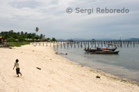 Pualu Mabul. Niño caminando por la arena cerca de las cabañas de pescadores. Sabah. 
