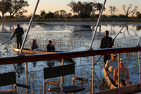 Safari aquàtic efectuat en mokoros al Delta de l'Okavango partint des del campament Eagle Island Camp d'Orient Express, als afores de la Reserva d'Animals de Moremi, a Botswana. L'acampada lliure al mig del Delta de l'Okavango és una experiència increïble. Et permet estar en contacte amb la natura i ens va permetre veure un dels capvespres més increïbles del nostre viatge per Àfrica del Sud. El especial d'aquest vespre va ser que ho vam veure des d'un mokoro al mig de les tranquil · les i transparents aigües del delta de l'Okavango en Botswana.El mokoro (mocoro o makoro canoes) és una piragua o canoa que originalment es feia de fusta de banús, encara que en l'actualitat són de fibra de vidre. Normalment va conduïda per un guia (Poler) que les condueix amb una perxa. Té a més capacitat per a dos passatgers i el material de suport per a la nit al campament. En el nostre cas ens assèiem sobre les màrfegues que després ens van servir per dormir. Consell: si teniu l'oportunitat de triar és important que el Poler parli almenys una mica d'anglès i que sigui jove i amb ganes de comunicar-se. La nostra experiència amb aquesta gent va ser francament molt bona, a la nit al costat del foc van estar explicant històries i compartint el sopar amb nosaltres en una illa al delta de l'Okawango. Com arribem? Sortim en avió des de l'Aeroport de Maum, per anar a l'aeroport o millor descrita la pista d'aterratge de Sepupa. Des d'aquí en camió fins a arribar a les ribes del riu per agafar el mokoro. No tinc paraules per descriure el que significa sobrevolar el delta interior més gran del planeta, però les poques que vaig poder trobar ja les faci servir en l'article Sobrevolar el Delta de l'Okavango. El impressionant del mokoro és la tranquil · litat que es respira i el silenci que permet apropar-se i veure animals salvatges, nosaltres vam veure hipopòtams, elefants, àguiles ... però el millor d'aquest dia va ser la posta de sol