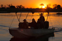 Bonita puesta de sol durante el safari acuático en el campamento Eagle Island Camp de Orient Express, en las afueras de la Reserva de Animales de Moremi, en Botswana. La visita de Okavango. La mejor época para visitar el delta depende de lo que se quiera observar. Si lo que se busca son animales grandes, el mejor periodo es entre mayo y octubre, cuando las aguas bajan y aquellos se concentran alrededor del agua. Si lo que se quiere ver son aves y una vegetación exuberante, la mejor época es entre noviembre y abril, la época de las lluvias. Hay unos cuarenta lodges y campamentos en el delta del Okavango. Los campamentos, donde se puede acampar o alquilar un lodge (casa o pabellón) propiedad del gobierno se encuentran en la reserva de Moremi, pero no en el corazón del delta, donde están los de carácter privado. Para acceder a ellos es preciso un todo terreno, un mocoro (barcas típicas de la zona), un helicóptero o una avioneta, reservada para los campamentos más caros, que no tienen otra vía de acceso. La intención del gobierno de Botswana es evitar el turismo de masas en el frágil ecosistema del parque, y por tanto la estancia y los alojamientos dentro del parque son muy caros. Muchos de los campamentos organizan salidas a pie y acampadas en islas desde las que hacer pequeños safaris. Los desplazamientos en vehículo todo terreno, dentro de las islas grandes y en los alrededores del delta, están condicionados en muchos casos por la altura del agua, que en tiempo de crecida cubre los arenosos caminos. En las zonas privadas incluso se pueden organizar salidas nocturnas con todo terreno, pero nunca en el parque nacional si no se es un científico.  El río Okavango nace en la meseta central de Angola, donde se le conoce como el Kubango, al sur de Vila Nova para, tras recorrer unos 1.600 km encontrarse ya en Botsuana, con la gran planicie previa al desierto del Kalahari, donde forma el delta interior más grande del mundo. Posteriormente desaparece tragado por las arenas del desierto y la evaporación sin llegar nunca al mar, destino natural de los ríos. El hecho de que se alimente fundamentalmente de las aguas producidas por las lluvias en Angola hace que el nivel más alto se alcance en agosto, plena época seca, mientras que en la de lluvias, cuando los animales pueden encontrar agua en numerosos pantanos estacionales, el delta presenta su nivel más bajo. Esto es lo que convierte al Delta del Okavango en un lugar único en el mundo donde viven unas 5.000 especies de insectos, 3.000 clases distintas de plantas, 540 de aves, 164 de mamíferos, 157 de reptiles y 80 de peces. 