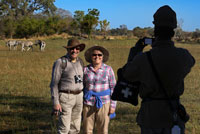 A couple of tourists photographing with zebras in background done walking safari camp near the Eagle Island Camp by Orient Express , outside the Moremi Game Reserve in Botswana . After scanning the horizon , Botsualo , our guide , you authorize us to set down tents and start a walk at sunset. " No need to worry , in this area there are no predators delta " he says when he sees our faces , among frightened and hopeful to walk through that area . Normally in parks but you can not walk in certain areas , guided self . This is a . Stealthy footsteps move huge recognizing droppings of elephants and monkeys , to a pasture area where several groups of zebra, wildebeest and antelope roam free . We discovered a skeleton giraffe. Further away , next to a huge baobab a rogue elephant . We can not approach too but being there, without the protection of the car, in nature, in his field , is a wonderful and liberating feeling equally. As the sun goes down we retired . Although it is the best time to observe the animals have to go back to camp, make a fire and cook dinner 