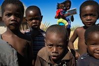 Un grupo de niños indígenas posan ante la cámara en el campamento Batawana. En las inmediaciones del campamento Eagle Island Camp de Orient Express, en las afueras de la Reserva de Animales de Moremi, en Botswana hay un campamento donde residen un centenar de indígenas de la tribu Batawana. Es posible realizar excursiones en canoa para visitar su poblado.  Los primeros habitantes de la actual Botswana fueron probablemente antepasados de los san (también conocidos como bosquimanos), cazadores y recolectores, que hoy habitan las estepas semiáridas de Botswana sudoccidental; y de los khoikhoi, provenientes del norte. Tribus de lengua bantú llegaron a la región en el primer siglo a.C. Los antepasados de los tswana, (hoy nación mayoritaria), se instalaron entre los siglos XI y XII en las llanuras del Río Vaal (hoy provincia sudafricana del Transvaal). Los tswanas se fundieron en ocho clanes poderosos. Las rivalidades entre clanes no permitieron a los tswana crear un reino como otras naciones en África del sur. La historia de Botswana –«la encrucijada fatal», ubicada en el corazón del sur de Africa–, es la historia del desierto de Kalahari, intermediario entre la poblada sabana del noreste y las despojadas estepas del suroeste. El tránsito precolonial posibilitó asentamientos de los británicos, holandeses y portugueses desde el siglo XVIII. Los británicos intentaron unir el continente de norte a sur (desde Sudáfrica a Egipto), tomando la «ruta de los misioneros». Los portugueses quisieron unir las colonias de Angola y Mozambique. La región fue una verdadera encrucijada entre los intereses estratégicos coloniales, y entre éstos y las tribus tswanas que habitaban esas zonas desde el siglo XVII. En 1840, se asentaron en el este de Botswana (región de Transvaal) los colonos holandeses boers (conocidos también como afrikaaners), que huían de los ingleses establecidos en Ciudad del Cabo (Cape Town). Los boers (agricultores) disputaron las escasas tierras fértiles con los tswanas, provocando además conflictos entre éstos y los zulúes a los que los colonos expulsaron del sur de África. En 1895 tres reyes tribales Tswana fueron a Londres buscando apoyo contra los boers y contra la expansión alemana por el sudoeste africano. Botswana se transformó desde allí en un protectorado británico, conocido como Bechuanaland. Los reyes debieron conceder, a cambio de protección, que la Compañía Británica de Sudáfrica (forma de privatización y expansión inglesa), construyera una vía férrea entre sus tierras y Zimbabwe (Rhodesia). La tutela inglesa impidió la absorción política por parte de Sudáfrica, pero facilitó la dominación económica de los boers. Pese a su vasta región semidesértica, Botswana se convirtió en uno de los principales exportadores de ganado y carne de África austral. 