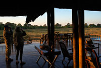 Un parell de turistes al porxo exterior del campament Khwai River Lodge d'Orient Express a Botswana , a l'interior de la Reserva Salvatge de Caça Moremi . Khwai River Lodge està situat a la vora del Riu Khwai , al costat de la Reserva de Caça Moremi i als afores del Delta d'Okavango . Khwai River Lodge és un dels hotel- safari més antics de Botswana , obert a finals dels anys 60 pel mort Sir Seretse Khama , primer president de la Botswana independent . Està situat sobre antigues plantes indígenes i figueres, a vuit quilòmetres al nord-oest de la porta nord de la Reserva Salvatge de Caça Moremi . A més , domina amb les seves vistes al riu Khwai i és el lloc perfecte per observar el paisatge perenne de la sabana africana i descobrir les seves variades espècies d'aus. El riu Khwai forma part del Delta d'Okavango . El campament es troba en Moremi , una de les reserves de més majestuositat d'Àfrica que presumeix d'albergar els exemplars més grans , ràpids , lluents i bells , com els abundants cocodrils i hipopòtams que habiten a les seves terres o els ramats de zebres i antílops que esquincen satisfetes la superfície de l'herba . Allà on aquests s'alimenten , amenacen tota mena de depredadors : lleons , lleopards i panteres , hienes i gossos salvatges