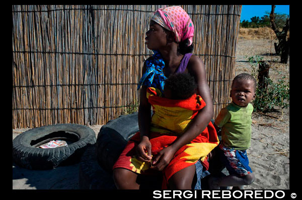 Retrato a una chica local en un poblado cercano al campamento Khwai River Lodge de Orient Express en Botswana, en el interior de la Reserva Salvaje de Caza Moremi. Botswana. La geografía de Botsuana está marcada por sus dos grandes mitos: el desierto del Kalahari y el delta del Okavango. Tras un largo camino desde Angola, el río Okavango llega al noroeste del país para verter sus aguas, no al océano como es normal, sino a las áridas tierras del Kalahari, donde en un mar de arena surgen 15.000 kilómetros cuadrados de canales, islas, flora y una fauna inimaginable. Tampoco el legendario desierto es el paraje yermo que cabría imaginar, sino una rica sabana semidesértica que cubre el 85% de la superficie total del territorio, donde extensas llanuras de pasto y bosques de mopane se alternan con finas arenas rojas, grises y blancas, promontorios rocosos y finalmente las dunas que todos esperamos encontrar. Sus fronteras son: al norte y oeste con Namibia, al este con Zimbabue, y al sur con Sudáfrica. En el sudeste del país se encuentra la zona más fértil y también la más densamente poblada. El 80% de la población vive en el medio rural. No es de extrañar que los bosquimanos, habitantes de Botsuana desde hace más de 30.000 años, hayan quedado arrinconados en las regiones más remotas del Kalahari. Su espiritualidad les ha permitido la convivencia pacífica con las etnias que se han ido asentando en su territorio a lo largo de los siglos. Cualquier disputa se resolvía con la fragmentación amistosa de los grupos tribales, en virtud de la cual los perdedores se establecían en otro sitio. Esta civilizada práctica fue posible hasta principios del XIX, cuando todos los pastos que bordean el Kalahari estaban ya repartidos y la expansión hacia Sudáfrica era imposible. Conscientes de lo vulnerables que les hacía la fragmentación en esas circunstancias, consiguieron reagruparse en una sociedad altamente estructurada regida por monarquías hereditarias. La historia más reciente de Botsuana, como la de la mayoría de los países africanos, ha venido marcada por los intereses de las potencias coloniales. En este sentido, cabe preguntarse: ¿Qué interés tendría administrar 50 millones de hectáreas de arena? La respuesta es fácil: su valor estratégico. Para Gran Bretaña representaba la posibilidad de conectar sus valiosas tierras del norte con el puerto de Ciudad del Cabo. Portugal buscaba un paso entre Angola y Mozambique. Para los alemanes sólo era una forma de no quedarse atrás en la carrera por el reparto del continente.