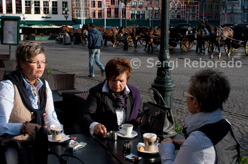 Brujas. Bares y restaurantes en Markt. Esta zona es la pieza central de la ciudad y en muchas ocasiones del año se ubica aquí un pequeño mercado. La plaza es un gran lugar para tener una idea de la ciudad y se encuentra junto a la enorme torre del campanario a un lado, el ayuntamiento al otro lado, además de restaurantes, tiendas y bares.