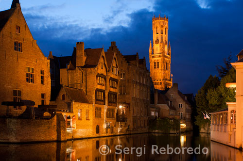 Brujas por la noche con la torre del campanario en el fondo, el paisaje más típico de Brujas. Por la noche es recomendable dar una paseo para observar las vistas sobre Brujas en el canal Dijver y la torre del campanario ilumninados. 