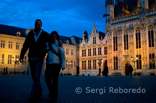 Brujas: El Ayuntamiento y la Plaza de Burg. Brujas es una ciudad con dos plazas. La más grande es el mercado, el corazón comercial de Brujas medieval. La segunda plaza se llama "Burg". Aquí estaba, y sigue estando, el corazón de la Brujas administrativa. Fue aquí que el conde Balduino I tenía un castillo fortificado y construido para proteger la zona contra los normandos y vikingos. El castillo ha desaparecido hace mucho tiempo, así como el principal edificio religioso de Brujas, la iglesia de San Donatius, que se situó en el lado opuesto de la casa consistorial. Donde estaba la iglesia hay ahora un pequeño muro, y una reconstrucción parcial de las paredes del coro de la iglesia. Se construyó aquí después de las fundaciones de San Donatius en 1955. La iglesia fue construida alrededor del año 900. La parte central era octogonal, al igual que la catedral de Carlomagno en la ciudad alemana de Aachen de la que se inspiró. El lugar de oración data del año 900 y fue sustituido en el siglo 12 por una iglesia de estilo románico. Esta versión de la iglesia de San Donatius fue destruida en 1799 durante la ocupación francesa de los Países Bajos del Sur. Algunos de los tesoros artísticos se fueron a otras iglesias (Catedral de San Salvador en Brujas). Varios personajes famosos están enterrados en San Donatius: la princesa Gunhilde (1087), el pintor flamenco Jan van Eyck (1441) y el filósofo español Juan Luis Vives (1540).