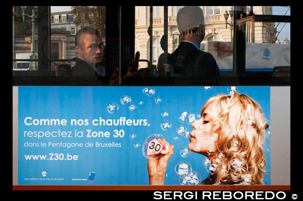 Interior de uno de los autobuses urbanos de Bruselas.Es una manera cómoda de viajar, sobretodo para unir recorridos de la ciudad en los que tuviéramos que hacer transbordo en las líneas del metro. Solamente se paran en las paradas marcadas siempre y cuando hayamos avisado que queremos detenernos pulsando el botón de parada, o bien haya algún pasajero esperando para subir. Fun-cionan durante las 24 horas del día, y lo más fácil para orientarse es buscar en las marquesinas de las paradas la información sobre el recorrido. El billete se puede abonar en metálico o bien hacerlo mediante la tarjeta combinada del metro con la cual podemos cambiar de línea de bus, de metro a bus o viceversa durante un periodo de una hora sin pagar más. Si el billete lo hemos comprado anteriormente deberemos volverlo a marcar en las máquinas de color naranja. Los autobuses con nombres de letras pertenecen a la compañía flamenca De Lijn, y los que comienzan por número a la STIB/MIVB. RUBIA EN UNA ANUNCIO DE LA ZONA 30 DE BRUSELAS