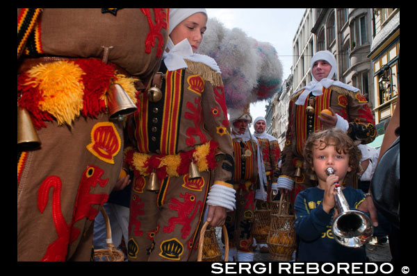 El festival belga de Binche con sus trajes tradicionales: príncipes orientales, marineros y arlequines recorre las calles de Bruselas. Una procesión increíble a través de las calles empedradas de la ciudad al compás de los tambores y artistas con sus máscaras de cera y sus plumas de avestruz. Toda una experiencia. NIÑO TOCA LA TROMPETA VESTIDO DE BINCHE.