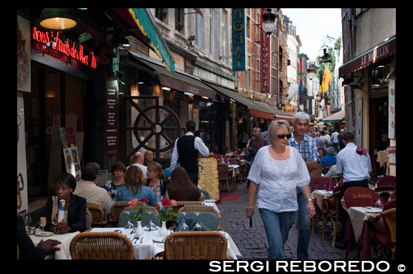 Rue des Bouchers. <M> De Brouckère. Aquest carrer en l'Edat Mitjana estava habitada per comerciants carnissers en la seva majoria, per això avui dia es conservi el seu nom (carrer dels carnissers). Encara hi ha bells records d'abans, com unes 12 mansions que daten del segle XVII i XVIII. Durant la Belle Époque, el carrer estava ple de nombroses petites sales de música, com el famós club de jazz La Rose Noire, on la famosa cantant belga Jacques Brel, va rebre el reconeixement a la dècada de 1950. Malauradament, el club va haver de tancar les portes i avui és ocupat pel restaurant Les Armes de Bruxelles. Els carnissers s'han anat marxant, i avui en dia aquest carrer de vianants la conformen multitud de bars i restaurants amb preus molt competitius que ofereixen bon marisc, a més dels famosos moules-frites (musclos al vapor amb sofregit acompanyats de patates fregides i maionesa) . ELS RESTAURANTS OFEREIXEN MARISC DE TOT TIPUS.