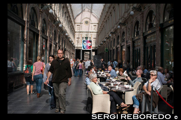 Cafeterias en las Galeries St-Hubert. Rue des Bouchers. <M> Gare Centrale. Inaugurada por el rey Leopoldo I de Bélgica en 1847, fue una de las primeras galerías comerciales cubiertas de Europa, y el primer edificio en Bruselas que albergó un techo de vidrio y metal. Fue realizada por Jean-Pierre Cluysenaar en estilo neorrenacentista y en su interior cohabitan desde hace más de siglo y medio una buena selección de las mejores tiendas de la ciudad recargadas de lujo y decoradas con gran esmero. Consta de dos partes principales: la Galerie du Roi y la Quenn’s Gallery, más una tercera pequeña sección llamada Galerie du Prince. TOMANDO EL APERITIVO EN LAS GALERIAS SAINT HUBERT.