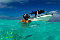 Aitutaki. Cook Island. Polynesia. South Pacific Ocean. Doing snorkeling in the Aitutaki (Lagoon Cruise).   The barrier reef that forms the basis of Aitutaki is roughly the shape of an equilateral triangle with sides 12 kilometres in length. The southern edge of the triangle is almost totally below the surface of the ocean, and the eastern side is composed of a string of small islands (including Mangere, Akaiami, and Tekopua). The western side of the atoll contains many of Aitutaki's important features including a boat passage through the barrier reef allowing for anchorage close to shore at Arutanga. Towards the south of the side is a small break in the barrier reef, allowing access for small boats to the lagoon which covers most of the southern part of the triangle. Further to the north is the bulk of the main island. Its fertile volcanic soil provide tropical fruits and vegetables. Two of Aitutaki's 15 islets (motus) are also volcanic. The rest are made of coral. Aitutaki Airport is located close to the triangle's northern point. There is an area suitable to land flying boats in the southeastern part of the lagoon.