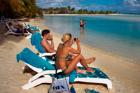 Aitutaki. Cook Island. Polynesia. South Pacific Ocean. Some tourists take pictures and take a sun bath on the beach of Aitutaki Lagoon Resort & Spa Hotel.  Reinvigorate and rejuvenate body and soul. There are two spa options on Aitutaki to reinvigorate and rejuvenate body and soul. You deserve it!. Spa Polynesia at the Aitutaki Lagoon Resort & Spa has two separate spa facilities, and offer special treatments on the beach or by the pool as well as at the spa Here is a small selection from their menu: Maorooro Aromatherapy Massage, Tama Coconut Scrub, SpaPolynesia ThalassoAlgae Body Wrap, Vaevae SpaPedicure, Rekareka Pamper Pac, Navenave Indulgence Pack. They also offer honeymoon pamper packs. At the Pacific Resort Spa the range of treatments and therapies includes the unforgettable 4-hour Pure Indulgence treatment. 