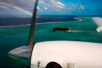 Aitutaki. Isla Cook. Polinesia. El sur del Océano Pacífico. Un avión vuela sobre las islas entre la isla de Aitutaki y Atiu Island con un arco iris de fondo. El primer hombre que llegó a Aitutaki de Avaiki [Hawaiki] era Ru. Llegó en una canoa llamado Nga-Puariki, en busca de nuevas tierras. La canoa era un gran doble, un Katea, a saber, dos canoas unen entre sí. El nombre de los travesaños de madera que sujetan en los estabilizadores son llamados Kiato. Los nombres de los Kiato fueron los siguientes: el principal Tane-mai-tai, el centro de uno de Te-pou-o-Tangaroa y el después de una Rima-auru. Llegaron a la isla y entró en un pasaje llamado Aumoana. Aterrizaron y erigieron un Ma, al que llamaron Pauriki, después de su canoa. (Ma significa un lugar de los malos espíritus.) También erigió un Ma hacia el interior, a la que llamaron Vaikuriri, que era el nombre del dios de Ru, Kuriri, traído de Avaiki. Ru llama la tierra Araura, lo que significa, el lugar al que el viento lo llevó en su búsqueda de la tierra. Nombró a un número de Koromatua como señores de la isla, (Koromatua = literalmente, personas mayores, o tupuna.) Sus nombres eran: E Rongo-Turu-Kiau, E Rongo-te-Pureiau, Mata-ngaae-kotingarua, Tai- teke-te-ivi-o-te-Rangi, Iva-ii-marae-ara, Ukui-e-Veri, Taakoi-i-tetaora. Estos fueron los señores de la isla como designado por Ru. Quedaba el resto de las personas que vinieron con él, que consiste en hombres, mujeres y niños. El pueblo de Ru deben haber un número superior a 200. Estas personas se asentaron en la tierra y crecieron en gran número. Se decía que era Ru quien elevó los cielos, ya que estaban descansando antes de su tiempo en las anchas hojas de plantas, llamado rau-teve.