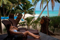 Isla de Rarotonga. Isla Cook. Polinesia. El sur del Océano Pacífico. Un cliente de la mujer se relaja en una tumbona junto al mar en el lujoso Little Polynesian Resort en Rarotonga. En el estilo típico de las Islas Cook, Little Polynesian Resort se encuentra en primera línea de playa de la laguna Titikaveka. Imagínese pasar las horas en el sofá con vistas a las impresionantes aguas color turquesa y playas de arena blanca. Para el alojamiento de Islas Cook lujoso e íntimo que puede `t ir más allá de este romántico resort boutique. Little Polynesian Resort ofrece dos tipos de alojamiento, el jardín se encuentran y el largo de la playa de Son. Todas están bellamente decoradas en tradicional polinesia y diseño isla y mobiliario. El jardín son una unidad escondido en los jardines tropicales y cuenta con una zona de cocina. El largo de la playa de Son se encuentra junto a la playa y cuenta con un gazebo privado con camas de día con vistas a la laguna. Nuestros espectaculares puestas de sol y las noches crepusculares harán de su boda o renovación de aquí, en el corazón del Pacífico Sur, una experiencia muy íntima y única. Si prefiere algo un poco más formal, una boda por la iglesia también se pueden arreglar. Confíe su día especial para nosotros con uno de nuestros paquetes de bodas y nosotros nos encargaremos de todos los detalles, que le da más tiempo para explorar nuestras hermosas islas. Todo lo que tienes que hacer es presentarse en el día. Cada uno de los 10 Luxury Beach Ares viene con su propio gazebo privado y cama de día con vistas a la playa de arena blanca de Titikaveka.