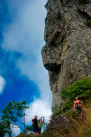 Rarotonga Island. Cook Island. Polynesia. South Pacific Ocean. A stone shaped human figure during the crossing of the forest in Rarotonga with Pa.   Cross the island of Rarotonga and explore the rugged interior. This is Pa’s special domain – the mountain – his temple!  The hike leads up the valley and across the island under a canopy of native trees to a steep 400 meter ascent of the Needle.  See ancient ceremonial stone, pictographs on the face of the Needle and hear legends of the ancient Polynesians.  Pa will explain how our different plants have been used through time for medicinal purposes. The crossing of a narrow ridge at the top is neither for the faint hearted nor for those with any physical challenges.  As you descend the mountain, you’ll cross refreshing mountain streams where you can refill your water bottles. Your trek concludes at Wigmore’s Waterfall, where you can cool off with a swim before getting back on your bus home.  For safety reasons, who goes on the walk is at Pa’s discretion. Hike takes about 3 hours.