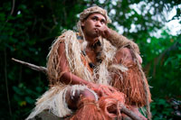 Illa de Rarotonga. Illa Cook. Polinèsia. El sud de l'Oceà Pacífic. Un home amb la roba dels maoris caçador a Highland Paradise Cultural Village mostrar. A mitjan 1980, el mort Raymond Pirangi Superior, 01:00 rangatira (sotscap) de la prominent Rarotongan Tinomana tribu, es va encarregar d'exposar per reclamar la seva herència de l'arbust dens descoratjador i vessants escarpades de Maungaroa. El seu somni i la determinació de compartir tot això amb la resta del món s'ha traduït en la resurrecció d'un dels més importants llocs d'interès històric de les Illes Cook. Situat a la part alta de les escarpades muntanyes de Rarotonga, amb vista sobre la llacuna aqua, que voregen els esculls de coral i l'oceà Pacífic, això, impressionant lloc de 205 hectàrees verges és d'un important patrimoni cultural i era un refugi espiritual i fortalesa segura per a les famílies, dels guerrers i la Tinomana principalment line per incomptables centenars d'anys. El Centre Cultural Highland Paradise ofereix una veritable experiència interactiva per als vilatans i visitants per igual. Aquí, vostè podrà reviure personalment als nostres ahirs polinèsies través autoguiada o guiada interactiva al lloc tranquil passeig passejos entre els exuberants jardins, restes del llogaret, rèpliques de ares (cases), àrees històriques de gran importància i els majestuosos arbres nadius.