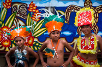 Rarotonga Island. Cook Island. Polynesia. A group of children dressed as dancers of the Cook Island around the Punanga Nui Markets.  Cook Islands dancing is almost similar to Tahitian dancing. The difference between Cook Islands and Tahitian dancing is in the hip swaying and the feet. Women dancers hip motion must be predominantly side-to-side and they must be flat footed while doing this. Tahitian women dancers hip motion is mostly round-and-round (like a washing machine) with the heel lifted. It is a real test to remain flat footed while swaying your hips. The way to tell a good female dancer is if her shoulders remain steady while she is swaying her hips.   The basic materials used to make dancing skirts are: long green leaves (rauti or coconut fronds), dried bark strips from the wild hibiscus tree (kiriau), pounded bark (tapa) or cotton cloth.  At the waist there is normally a titi which is adorned with all kinds of shells, seeds, leaves or flowers.  Apart from being a decorative item, it also adds a little weight which helps the shaking/swinging process.  A lot of work goes into producing costumes, but they last many years.  Behind the dancers are the drummers, guitar/ukelele players and singers.  There are various drumming instruments used.  