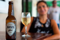 Rarotonga Island. Cook Island. Polynesia. South Pacific Ocean. A girl sipping a Matutu Mai beer, typical beer of the Cook Island. Matutu Brewing Company is based in Vaka Takitumu on the island of Rarotonga. We are two families of patriotic Cook Islanders aiming to produce premium beers and beverages that will be iconic to the Cook Islands experience. Our beer is currently available in all reputable cafes, restaurants, resorts and bars in Rarotonga and in some outer islands resorts and cafes. Brewing is a long established practise in the Cook Islands called "tumunu".  Matutu is the only brewing company located in the Cook Islands. You can find us in the village of Tikioki, on the Island of Rarotonga. Matutu boutique beers are brewed in small batches using only premium brewing ingredients. We handcraft each brew, and bottle to order to ensure that our beer arrives fresh to you. At present we brew 'Mai' our Lager, 'Kiva' our Pale Ale and the recently launched 'Matutu' our draught. Mai – Lager Mai is an authentic Lager brewed with German Pilsner malt and the addition of four hops which give this beer its distinctive notes. Super Alpha and Hallertau hops are added early to this brew which ensures it's crisp, bitter taste, while the later additions of Saaz (B and D) give off the estery aromas and flavours. These combined with brewer's passion give you genuine flavours to savour while quenching your thirst.