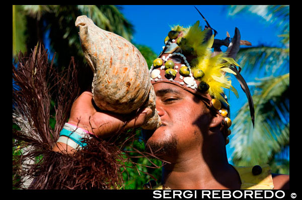 Aitutaki. Cook Island. Polynesia. South Pacific Ocean. An actor dressed Polynesian blowing a conch shell in Aitutaki Punarei Culture Tours. This is a unique opportunity for you to learn about the ancient culture, myths, legends and traditional ways of our ancestors. The tour is a great way to discover the history, traditional skills, Art & beliefs of the island of Aitutaki. The tour concludes with a traditional feast (umu kai) for lunch on site. The second voyagers of note were Te Erui and his brother Matareka. Te Erui set out from Havaiki in the canoe Viripo, An unexpected hurricane, hur1'hia, dismasted his vessel, but he managed to get back to Havaiki. On being told by a priest that the cause of the disaster was due to the naming of his canoe, he immediately built another canoe. The vessel, on the advice of the priest, was named Te Rangi-pae-uta, and the two masts were named after the gods Rongo and Tangaroa. Thus, with divinity sitting in the belly of his sail, he braved the sea once more in his quest of land. He landed on the West side of Aitutaki, at a point on the reef known as Te Rua-karae. Here he was opposed by one of Ru's descendants, who said, "Tera te moana uriuri o Hiro. Haere ki i'eira kimi henua ai " – "There lies the purple sea of Hiro. Go there to.seek land." The request went unheeded. After slaying various opponents, Te Erui cut a channel through the reef with his adze, Haumapu, and finally settled down at Reureu. The channel which is credited to Te Erui's engineering ability is Te Rua-i-kakau, the boat passage which has been such an inestimable boon to Aitutaki. The various historical spots mentioned are shown on the map of Aitutaki. Ruatapu, the third voyager of note, came from Taputapuatea to Rarotonga, and then successively to Raro-ki-tonga, Mauke, and Atiu. During these voyages his canoe had the name of Te Kareroa-i-tai. At Atiu, the canoe name was changed to Tuehu-moana, and in it he sailed to Manuae and then Aitutaki. At Aitutaki he sailed through a passage near the north end, called Kopua-honu, and re- named, after him, Kopu-o-Ruatapu. He is credited with having brought the coconut and the flowering plant known as tiare maori. After quarrelling with his son Kirikava over fishing nets, he came on to Ruatea, near Black Rock. From there he attracted the attention of the ariki Tarula by means of certain toys, and they became friends. He excited the curiosity of Taruia with tales of the islands he had visited, and finally persuaded the ariki to accompany' him on a voyage to see the beautiful women of the islands (nga wahine purotu o nga motu.) Ruatapu purposely sailed before Taruia was quite ready, and to the latter's appeal to wait he called back, " I will go on to Rarotonga and be on the beach to welcome you in." On the other side of the islet of Maina, at a spot called Rau-kuru-aka, Ruatapu purposely capsized his canoe. Taruia shortly afterwards appeared, and to Ruatapu's appeal to wait until he had righted his canoe, he replied with no small satisfaction, "No; I will go to Rarotonga and be on the beach to welcome you in."Ruatapu waited until Taruia was out of sight. He then righted his canoe and, returning to Aitutaki, he had himself made Ariki of the island. Ruatapu is a well-known Maori ancestor of similar parentage,with whom a canoe-sinking incident is also associated in tradition.