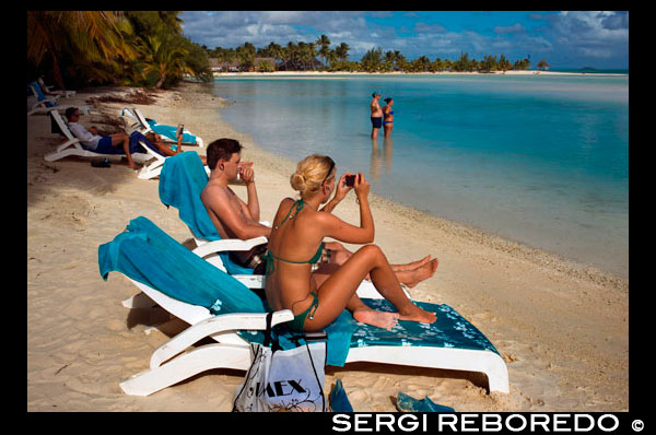 Aitutaki. Cook Island. Polynesia. South Pacific Ocean. Some tourists take pictures and take a sun bath on the beach of Aitutaki Lagoon Resort & Spa Hotel.  Reinvigorate and rejuvenate body and soul. There are two spa options on Aitutaki to reinvigorate and rejuvenate body and soul. You deserve it!. Spa Polynesia at the Aitutaki Lagoon Resort & Spa has two separate spa facilities, and offer special treatments on the beach or by the pool as well as at the spa Here is a small selection from their menu: Maorooro Aromatherapy Massage, Tama Coconut Scrub, SpaPolynesia ThalassoAlgae Body Wrap, Vaevae SpaPedicure, Rekareka Pamper Pac, Navenave Indulgence Pack. They also offer honeymoon pamper packs. At the Pacific Resort Spa the range of treatments and therapies includes the unforgettable 4-hour Pure Indulgence treatment. Other options in their range of treatments includes aromatherapy treatments, facials, skin treatments for men and women, body massages, and luxurious manicures and pedicures. Explore the beaches and inland roads. There is more to Aitutaki than its gorgeous lagoon. The island itself is charming and you can explore its beaches and inland roads at a very leisurely pace. Aitutaki also has some hidden archaeological treasures. There is an island tour in a small shuttle bus that is a fun way to see Aitutaki and find out about island life. To explore the inland tracks built by the American servicemen during World War 2, and also to find out about the ancient pre-Christian marae (sacred sites) and their archaeological excavations, you are best to take a 4-wheel drive tour. Ngaakitai Pureariki is owner/operator of Aitutaki Safari Adventures and was the driving force behind the clearing and replanting of Te Poako o Rae Marae on the eastern side of the island. This site covers around 1.6 hectares (4 acres) and has intriguing groupings of large stones standing upright in the ground. Carbon dating has revealed the marae was established around 1000AD. Ngaakitai was also director of the excavations on the site of the Paengaariki marae, working with archaeologist Mark Eddowes and a field crew of Aitutaki locals. These excavations are still in progress and are expected to reveal information about when the marae was built and the ceremonies and activities that took place there. There are already indicators of the ancestors' ancient beliefs and practices. The project is ongoing and all artefacts recovered will be measured, drawn to scale and photographed. They will remain on the island. 