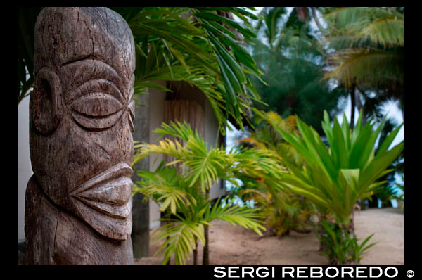 Isla de Rarotonga. Isla Cook. Polinesia . El sur del Océano Pacífico. Totem situado fuera de la lujosa Little Polynesian Resort en Rarotonga. El Little Polynesian está rodeado con el tipo de belleza natural que el Pacífico Sur es famosa. En 2005, el Little Polynesian fue restaurado para dar a conocer lo que sólo puede ser descrito como una recreación literal de lograr una vez más un nuevo nivel de servicio y comodidades. Nuestros Ares magníficamente construidas (bungalows) , se han diseñado con especial atención a los detalles intrincados . Cada unidad utiliza la arquitectura tradicional de las Islas Cook se combina con una decoración sobria pero elegante ricamente . Little Polynesian un pequeño escondite de lujo en Titikaveka en la isla de Rarotonga tiene vistas a una magnífica playa de arena blanca de natación con un excelente buceo en alta mar y hay kayaks gratuitos para explorar la laguna de color turquesa. La política de que ningún niño se asegura la privacidad absoluta - lo que es el lugar ideal para lunas de miel y escapadas románticas . Todas las habitaciones son para no fumadores . El Little Polynesian ofrece todas las comodidades que se esperan de boutique resort más exclusivo de las Islas Cook . The Beach Ares lujo prometen días sin rumbo de vistas a las aguas turquesas de la laguna y despertarse con el suave sonido de las olas, mientras que el aroma de las flores tropicales llena el aire alrededor de nuestras villas con jardín . Acentos tradicionales en los bungalows , incluyendo Wild Hibiscus, Mangaian ( coco) Sinnet tejiendo en vigas , así como un techo de paja con Pandanus naturales se suman al ambiente de nuestra Mares del Sur paraíso. El aroma de las flores tropicales llena el aire alrededor de la fourGarden Pia Tiare (Garden Villas) - proporcionando una experiencia especial que está cerca de la naturaleza. Al igual que la playa de Ares, cada uno está equipado con una amplia cama de matrimonio , puerta de la ducha y la bañera de hidromasaje y frigobar . Un cielo despejado azul, una laguna turquesa , aguas tranquilas y un clima templado , lo hacen ideal para una serie de actividades acuáticas como natación , snorkel, buceo , pesca deportiva, pesca deportiva y kayak. Otras actividades , como senderismo , rutas a caballo , visitas culturales , excursiones de observación de aves , vuelos panorámicos , golf, tenis, squash y bolos . ¿Qué podría ser más romántico que decir " " sí, quiero " en una playa o boda del jardín en el Little Polynesian?.