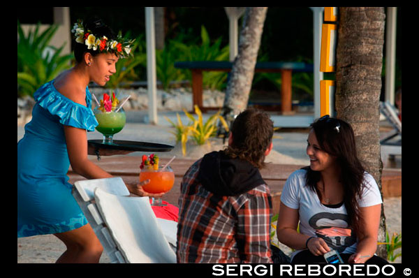 Rarotonga Island. Cook Island. Polynesia. South Pacific Ocean. A tourist couple enjoying huge cocktails by the beach in the Hotel Crown Beach Resort & Spa.  Crown Beach Resort & Spa presents a private secluded space for just 36 couples to escape in 5 acres of tropical gardens and an endless icing sugar beach that caresses a sparkling blue lagoon. Ridiculously romantic, Crown Beach Resort & Spa is located on the sheltered sunset coast of Rarotonga where 5 acres of botanical gardens and an endless icing sugar beach caresses a sparkling blue lagoon. Crown Beach Resort & Spa offers a private and secluded haven for just 42 couples to frolic in uninterrupted space and unhurried time. Our villas and suites present king bedrooms adorned with lavish textures in neutral tones that warm the soul - choose from your own private swimming pool or Jacuzzi. This place is sure to unleash your desire with the one you love. Crown Beach Resort & Spa is your key for pure bliss and luxurious romantic salvation.