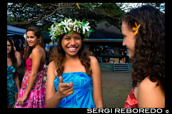 Rarotonga Island. Cook Island. Polynesia. Some nice teenagers dressed in Polynesian around the Punanga Nui Markets.  Cook Island market day is every Saturday down at the Punanga Nui Markets (located in Avarua, which the locals call Town) for locals and visitors alike. Locals tend to head to the markets early (before breakfast) to pick up bargains on fresh fruit and vegetables. Here local delicacies can be one third the price you will find them at the supermarket. Most visitors take a more leisurely approach and tend to get to the markets mid morning. To get there you can either catch the Island Bus to Avarua or drive. Parking space is easily found down at the eastern end of the market. At the eastern end of the market you will find an array of craft and clothing stalls selling colourful sundresses, pareu's, ukuleles, black pearls and jewellery. Be sure to look out for the Cook Islands tivaivai (quilts). They are beautifully handmade bedspreads of tropical designs and colours. The tivaivai art form is unique to the Cook Islands and are works of love by the women who spend hours making the sought after bedcovers. The atmosphere at the markets is friendly and relaxed. You will rarely find sellers here who try to push their wares and bargaining is not an accepted custom in the Cook Islands. You are naturally drawn toward the centre of the markets with the sounds of singing and laughter, and the gorgeous aroma of curries, BBQ's and satays. This outdoor food court is great place to sample some local delicacies, take a seat and soak in the atmosphere. An example of what's on offer and price guide: Waffles and ice cream $6, Curry $5, Satay Stick $2, Fresh Coconut $2.50, Pawpaw Smoothie $4, Past the food court you come to the fresh fruit and veggie stalls. Growers come from all over the Cook Islands to sell their produce at this market. It's also a great place to buy Nonu Juice, the Cook Islands original natural tonic. You may find it for as little as $8 a bottle. Now that's a bargain.