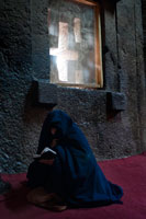 Lalibela. Una dona resa a l'interior de l'església Bet Medhane Alem. Per admirar les esglésies de Lalibela no cal mirar cap amunt, sinó cap als peus. L'església més gran és Bet Medhane Alem, la més gran de totes, amb 33 metres de llarg per 25 d'ample i una fastuosa decoració que recorda als temples grecs. La de Bet Emmanuel, uns centenars de metres a l'est de l'anterior, és una de les més belles i millor tallades de totes, que segurament va servir com a capella real. Fa més de 700 anys, un rei etíop va decidir fer de la seva ciutat la "Jerusalem" del món cristià ortodox. Però en comptes d'aixecar grans temples a la manera clàssica, se li va ocórrer excavar a la roca perquè els enemics que fustigaven el seu regne no els localitzessin fàcilment.