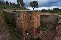 Lalibela. Iglesia de San Jorge. La Iglesia de San Jorge es la mejor conservada del conjunto de templos ortodoxos labrados en piedra de Lalibela, en Etiopía. Este yacimiento rupestre, que hunde sus orígenes en la época medieval, fue construido como una representación de Tierra Santa por la Dinastía Zagüe. En la actualidad, los templos de Lalibela continuan con su actividad religiosa y reciben visitas de peregrinos que se confunden con turistas curiosos por descubrir el entramado de pasadizos entre piedras que unen unos con otros. 