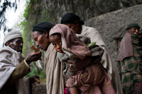 Una dona besa la cuz d'un sacerdot a l'església de Nakuto Lab, als afores de Lalibela. A 2.400 metres d'altitud, en el planell etíop, al nord d'Addis Abeba, es troba aquesta petita localitat monàstica (la segona ciutat d'Etiòpia considerada Santa), coneguda en l'antiguitat com Roha i que, va canviar el seu nom després de ser conquerida al segle XIII pel monarca Gebra Maskal Lalibela, qui la "batejar" com Lalibela. Va ser, per mandat d'aquest rei, quan es va començar la construcció d'aquestes singulars esglésies, singulars pel fet que estan excavades a la terra, fet que les converteix en úniques i que els va merèixer el 1979, el reconeixement com a Patrimoni de la Humanitat per la UNESCO.