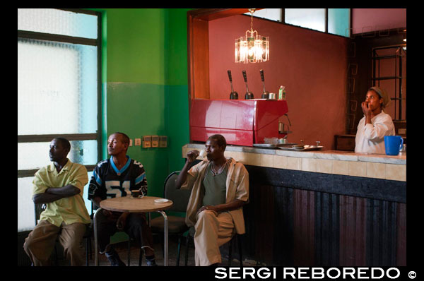 Interior of a restaurant. Men kill times with an old TV. The injera is the typical dish found in any restaurant, bar, and in every house. The Ethiopian injera bread is. It has a very distinctive sour taste and special. It is made with teff flour (teff is a local cereal-grain gluten-very small, it is very difficult to find outside of Ethiopia). The injera is shaped like a large French crêpe. Plate is used as where foods are placed and pinching pieces is used for spoon feeding mode. In Ethiopia is baked on clay plates placed over the fire but at home we will do with an iron skillet or larger than we.