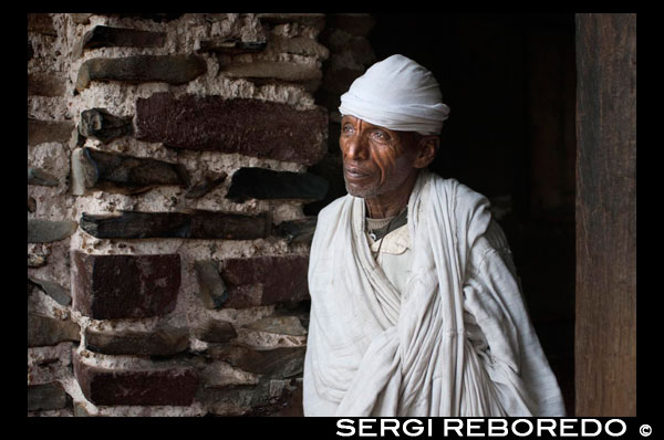Un sacerdot a la porta de l'església Debre Berhan Selassie. Explica la llegenda que, quan a finals del segle XIX els dervixos sudanesos van intentar destruir aquesta església, un eixam d'abelles dels va fer fora del lloc, perseguint enfurismades, fins que els dervixos no van tenir més remei que desistir del seu intent. Debre Berhan Selassie és una església íntima atapeïda d'art etíop. Vides de sants, màrtirs i tradició popular es disputen les parets mentre que desenes de querubins alats tornen la mirada al visitant des del sostre.